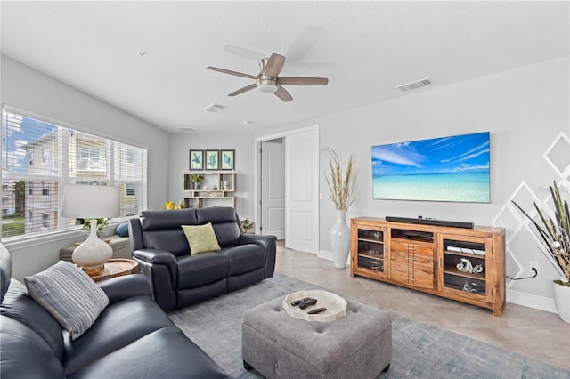 living room featuring ceiling fan, light tile patterned floors, and a textured ceiling