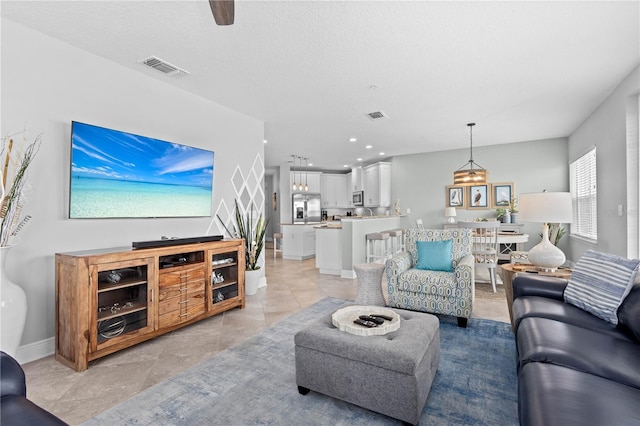 tiled living room with a textured ceiling and ceiling fan