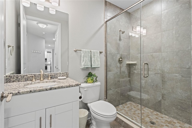 bathroom featuring vanity, toilet, and a shower with door