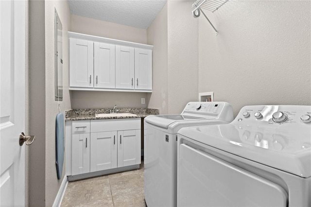 washroom featuring light tile patterned floors, sink, a textured ceiling, cabinets, and washing machine and dryer