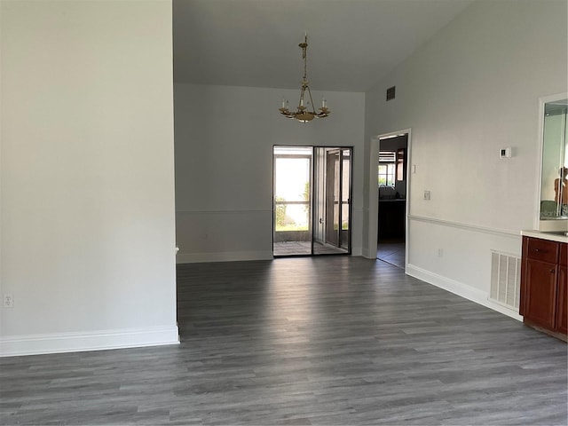 spare room featuring dark hardwood / wood-style flooring, high vaulted ceiling, and a chandelier