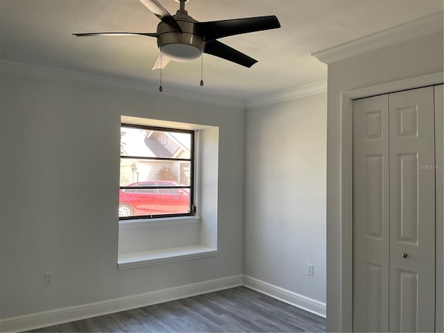 unfurnished bedroom featuring baseboards, ceiling fan, ornamental molding, dark wood-type flooring, and a closet