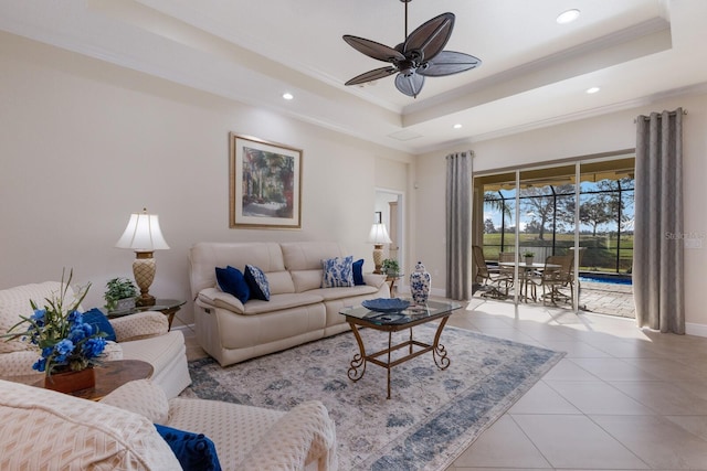 tiled living room featuring ceiling fan, a raised ceiling, and ornamental molding