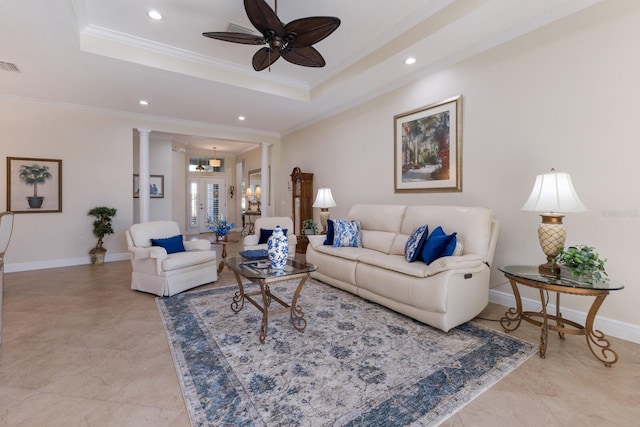 living room with a raised ceiling, ornate columns, ceiling fan, and ornamental molding