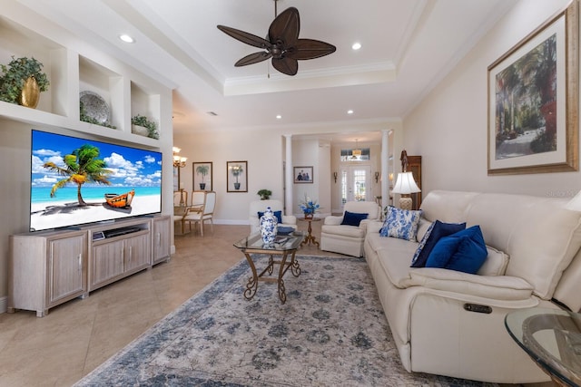 tiled living room with a tray ceiling, ceiling fan with notable chandelier, and ornamental molding