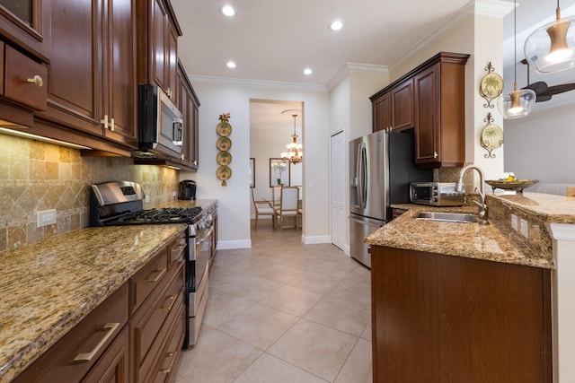 kitchen featuring crown molding, decorative light fixtures, light stone countertops, a notable chandelier, and stainless steel appliances