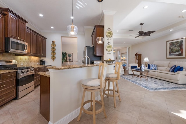 kitchen with backsplash, a kitchen breakfast bar, light stone countertops, decorative light fixtures, and stainless steel appliances