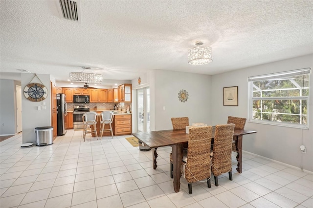 dining space with light tile patterned floors, a textured ceiling, and a chandelier