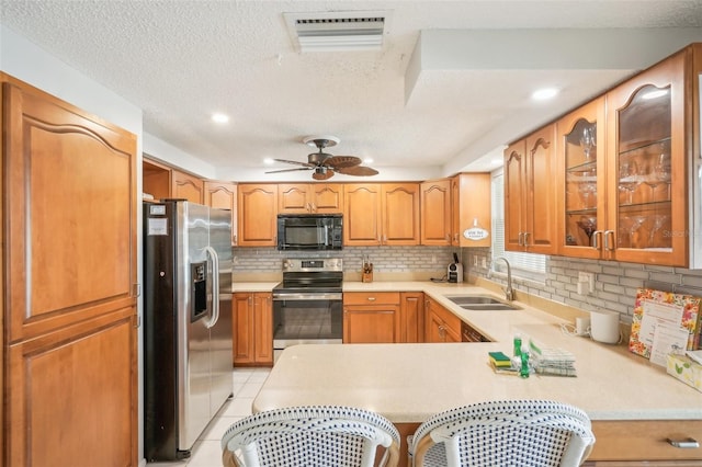 kitchen with sink, stainless steel appliances, kitchen peninsula, backsplash, and light tile patterned floors