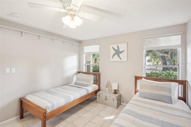 tiled bedroom with ceiling fan and a textured ceiling