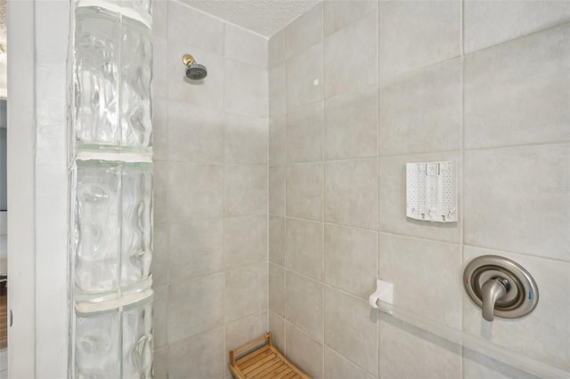 bathroom featuring a textured ceiling and tiled shower