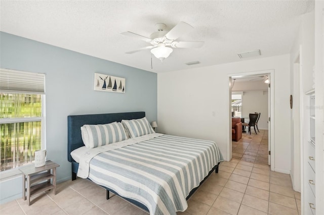 tiled bedroom with ceiling fan and a textured ceiling