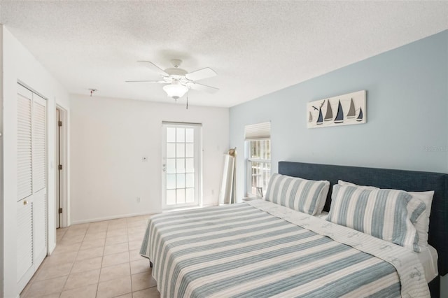 bedroom featuring light tile patterned flooring, ceiling fan, a closet, and a textured ceiling