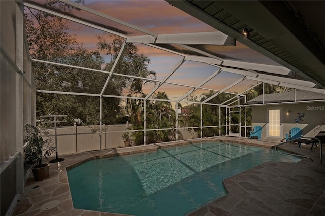 pool at dusk with a patio and a lanai