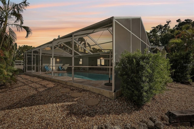 pool at dusk with a patio and a lanai