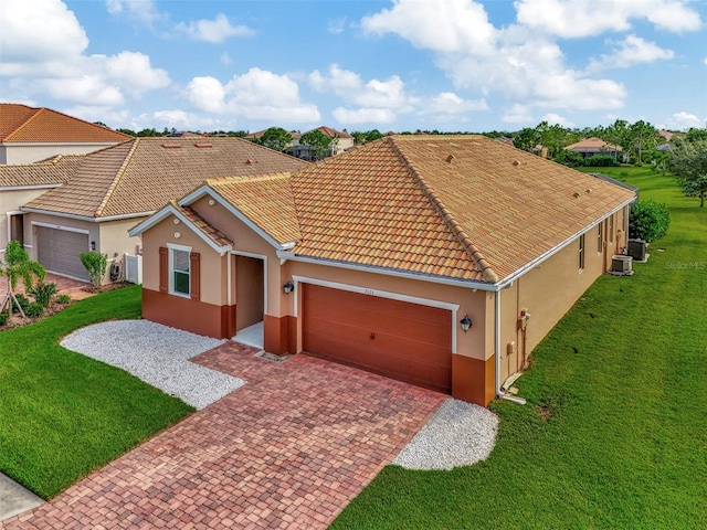 mediterranean / spanish house featuring a front yard, a garage, and central AC unit