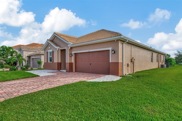 view of front of home with a front lawn, central AC unit, and a garage