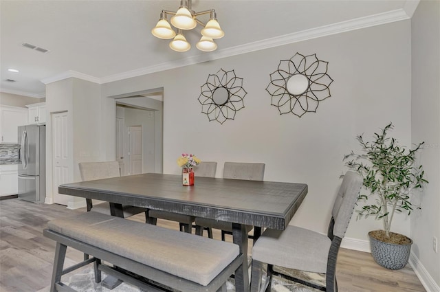 dining room featuring crown molding, a notable chandelier, and light hardwood / wood-style flooring