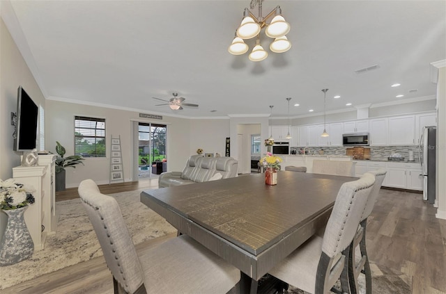 dining room featuring crown molding, wood-type flooring, and ceiling fan with notable chandelier