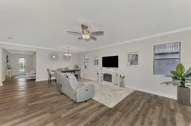 living room with dark wood-type flooring, crown molding, and ceiling fan with notable chandelier