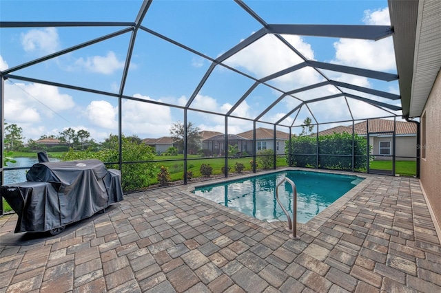 view of pool with a water view, area for grilling, glass enclosure, and a patio area