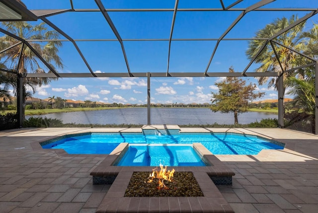 view of pool with glass enclosure, a patio area, and a water view