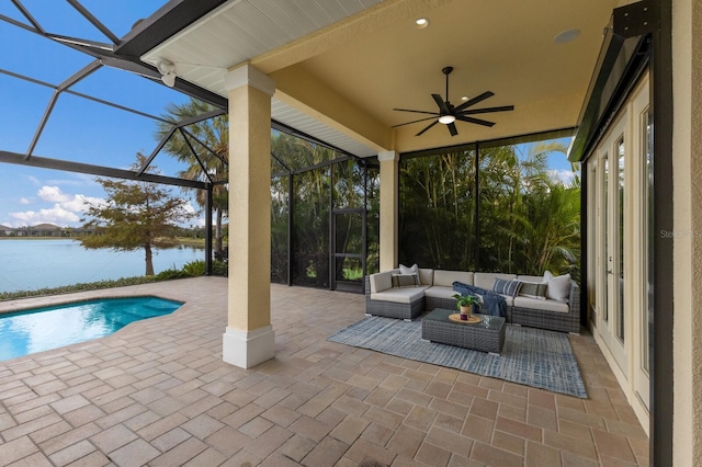 view of patio / terrace with a lanai, an outdoor living space, ceiling fan, and a water view