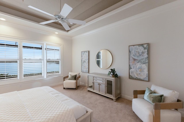 bedroom featuring ceiling fan, light colored carpet, crown molding, and a tray ceiling