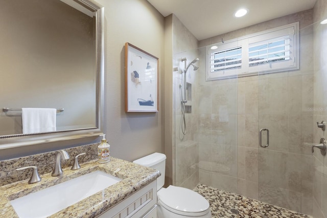 bathroom with vanity, toilet, and a shower with door