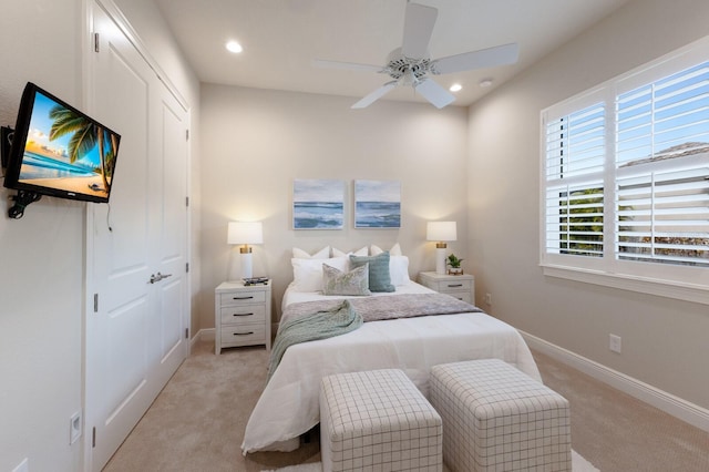 bedroom featuring ceiling fan, light colored carpet, and multiple windows