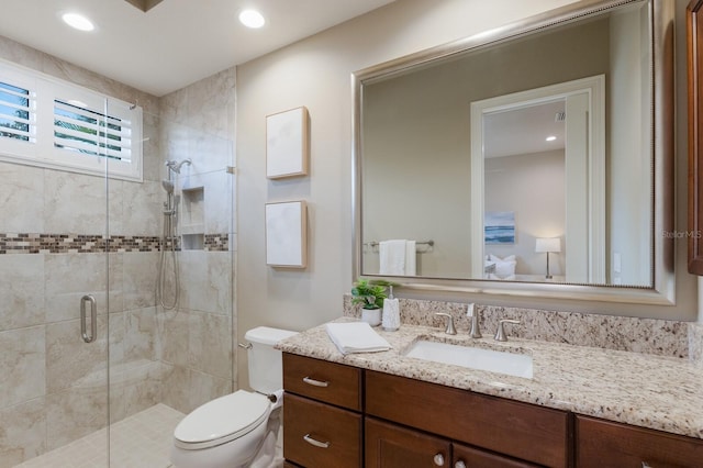 bathroom with vanity, a shower with shower door, and toilet