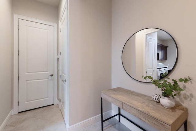 corridor with washer / dryer and light tile patterned floors