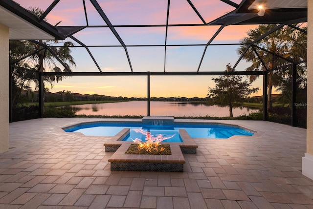 pool at dusk featuring a lanai, a water view, and an outdoor fire pit