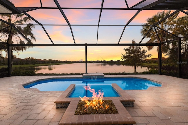 pool at dusk with a lanai, a water view, and a patio