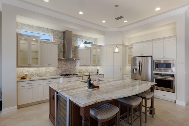 kitchen with a center island with sink, wall chimney range hood, sink, appliances with stainless steel finishes, and beverage cooler