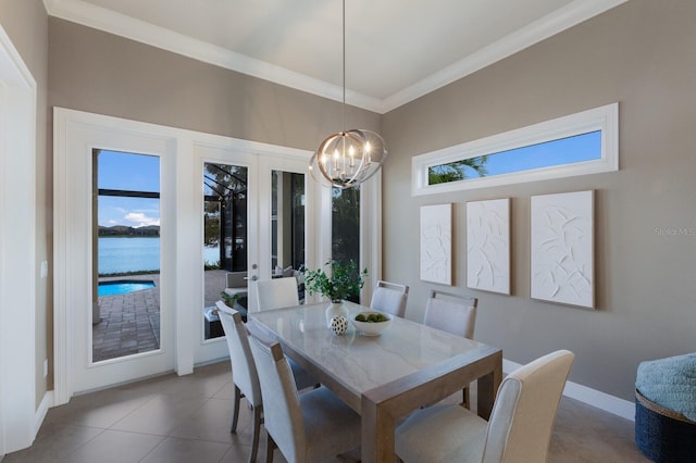 tiled dining space with a chandelier, french doors, a water view, and ornamental molding