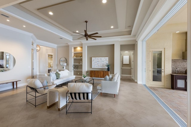 tiled living room featuring a raised ceiling, ceiling fan, built in features, and ornamental molding