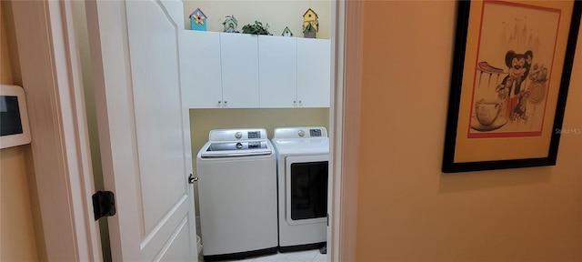 clothes washing area featuring washer and clothes dryer, cabinet space, and light tile patterned floors