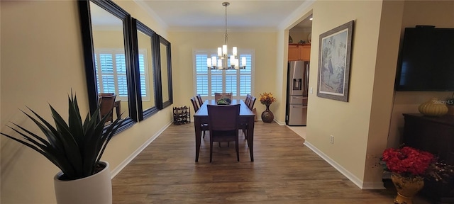 dining space featuring dark wood-type flooring, ornamental molding, baseboards, and a notable chandelier