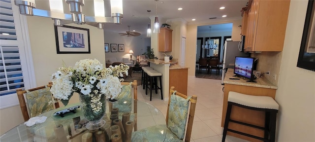 dining space featuring light tile patterned flooring, ornamental molding, and an inviting chandelier