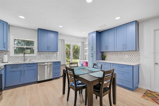 kitchen featuring dishwasher, decorative backsplash, light hardwood / wood-style flooring, sink, and blue cabinetry