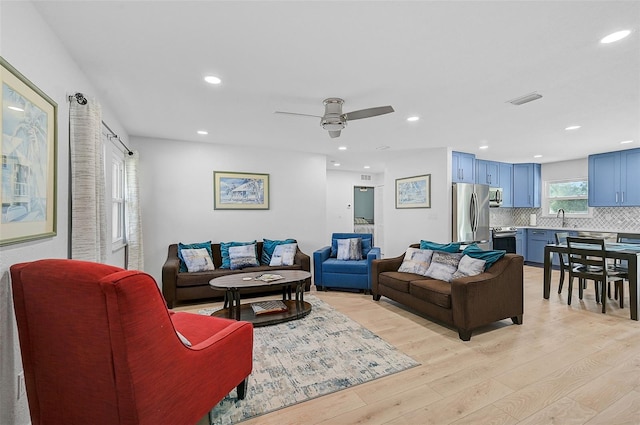 living room featuring light hardwood / wood-style flooring, sink, and ceiling fan