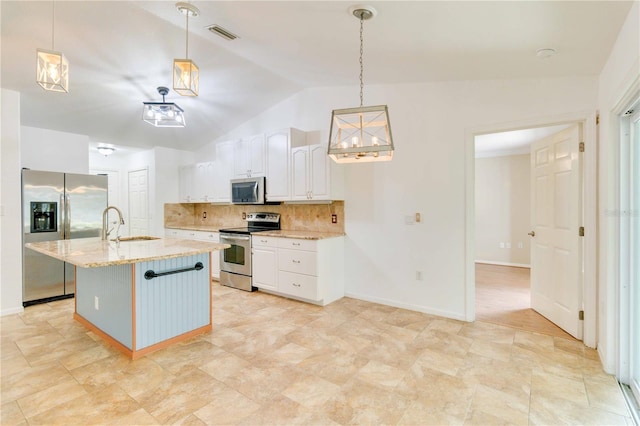 kitchen featuring white cabinets, lofted ceiling, hanging light fixtures, appliances with stainless steel finishes, and light stone countertops