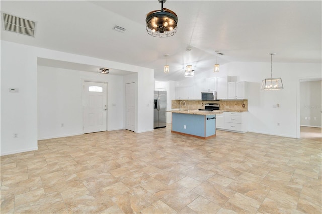 kitchen with decorative light fixtures, a kitchen island with sink, white cabinetry, stainless steel appliances, and vaulted ceiling