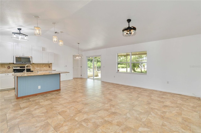 kitchen featuring appliances with stainless steel finishes, white cabinetry, vaulted ceiling, an island with sink, and decorative light fixtures