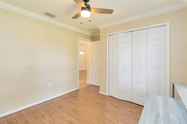 unfurnished bedroom with ceiling fan, light hardwood / wood-style flooring, crown molding, and a closet