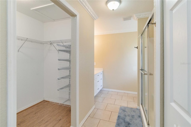 bathroom featuring ornamental molding, wood-type flooring, a shower with shower door, and vanity