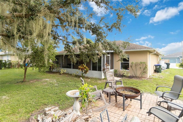 back of property featuring a patio, a yard, a sunroom, and an outdoor fire pit