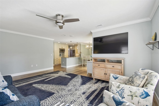 living room with ornamental molding, hardwood / wood-style floors, and ceiling fan with notable chandelier