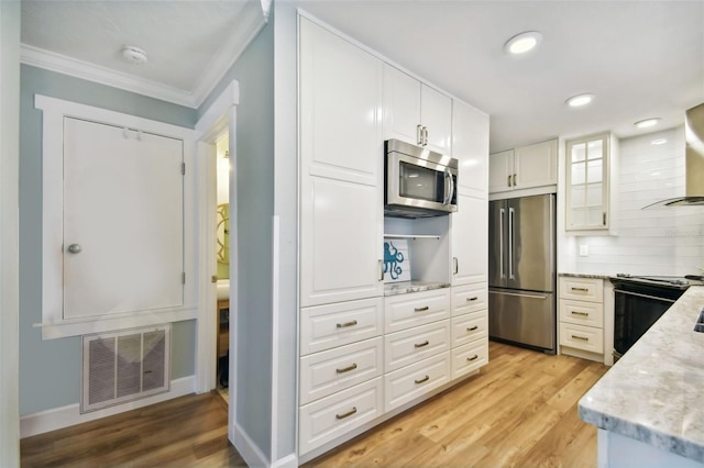 kitchen with decorative backsplash, light stone counters, white cabinetry, light hardwood / wood-style floors, and stainless steel appliances